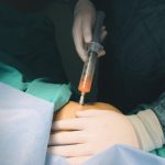 Doctor performs injection procedure, highlighting healthcare precision.