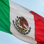 The mexican flag is flying high in the sky